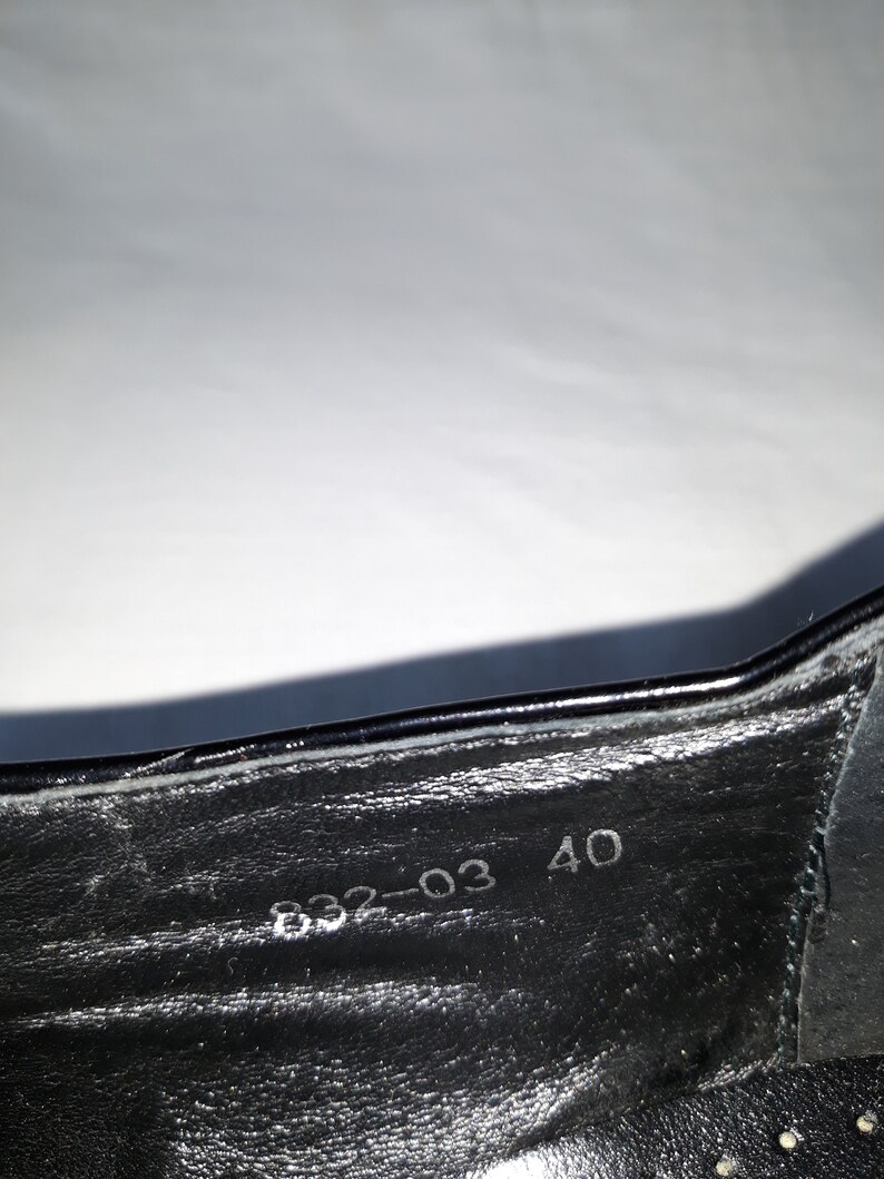 Puede incluir: Primer plano del interior de un zapato negro con la talla 40 y el n&uacute;mero 832-03 impreso en la plantilla.