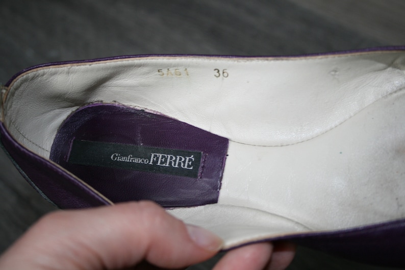Op de afbeelding: Close-up van de binnenkant van een paarse leren schoen. De schoen heeft een witte leren binnenzool met maat 36. Een zwart label met "Gianfranco FERRE" is zichtbaar.