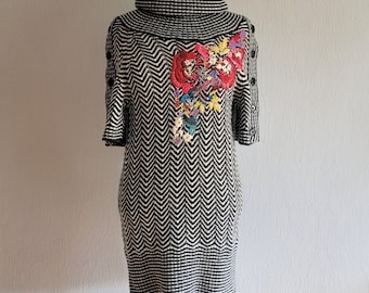 May include: Black and white chevron patterned sweater dress with a colorful floral embroidery on the front.