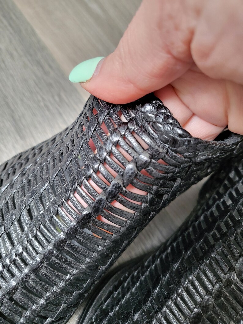 May include: Black woven leather ankle boots with a cut-out design. The boots are made of a soft, flexible material and have a comfortable fit.