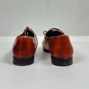 May include: A pair of brown leather dress shoes with laces. The shoes have a classic design with a rounded toe and a low heel. The leather has a glossy finish.