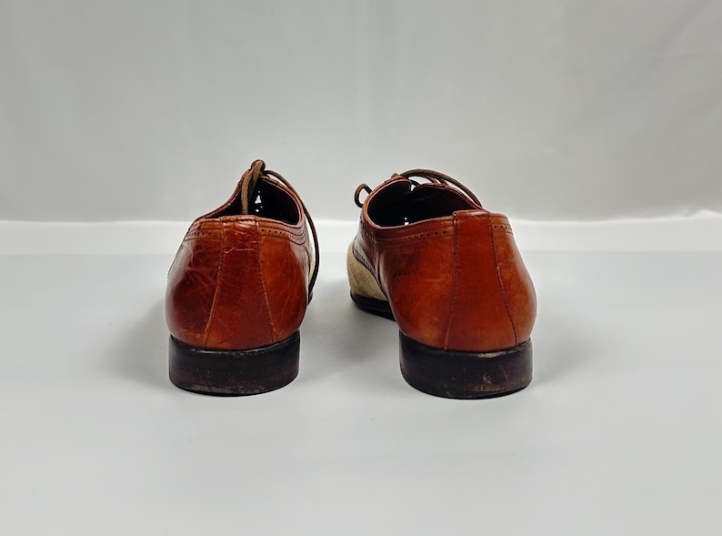 May include: A pair of brown leather dress shoes with laces. The shoes have a classic design with a rounded toe and a low heel. The leather has a glossy finish.
