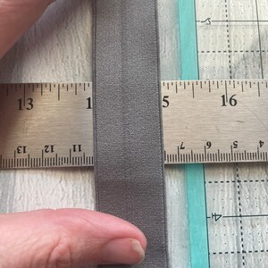 Puede incluir: Primer plano de una banda el&aacute;stica gris medida con una regla. La banda el&aacute;stica tiene 1,27 cm de ancho.