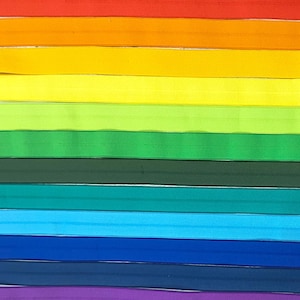 Puede incluir: Un conjunto de 12 gomas el&aacute;sticas de colores en un esquema de colores arco&iacute;ris. Las gomas est&aacute;n dispuestas en una pila horizontal, con el rojo en la parte superior y el rosa en la parte inferior.