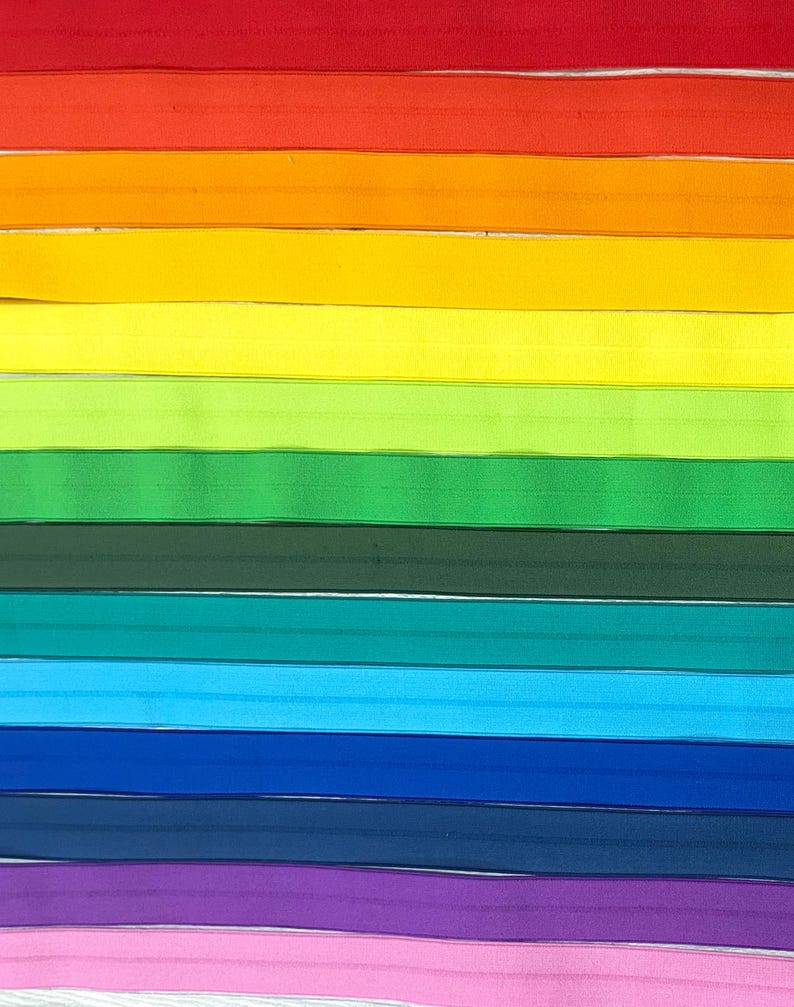 Puede incluir: Un conjunto de 12 gomas el&aacute;sticas de colores en un esquema de colores arco&iacute;ris. Las gomas est&aacute;n dispuestas en una pila horizontal, con el rojo en la parte superior y el rosa en la parte inferior.