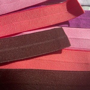 Puede incluir: Un conjunto de gomas el&aacute;sticas de colores en tonos rosa, rojo y marr&oacute;n. Las gomas est&aacute;n dispuestas en capas, con la m&aacute;s oscura en la parte inferior y la m&aacute;s clara en la parte superior.