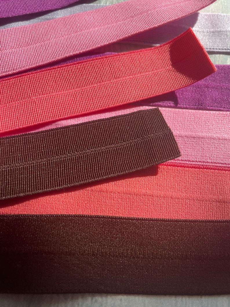 Puede incluir: Un conjunto de gomas el&aacute;sticas de colores en tonos rosa, rojo y marr&oacute;n. Las gomas est&aacute;n dispuestas en capas, con la m&aacute;s oscura en la parte inferior y la m&aacute;s clara en la parte superior.