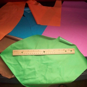 May include: Assortment of colorful fabric scraps in orange, brown, blue, green, and pink. A ruler is included in the image.