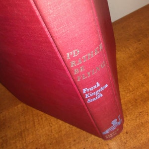 May include: A red hardcover book with the title "I'd Rather Be Flying" and the author's name "Frank Kingston Smith" in gold lettering.