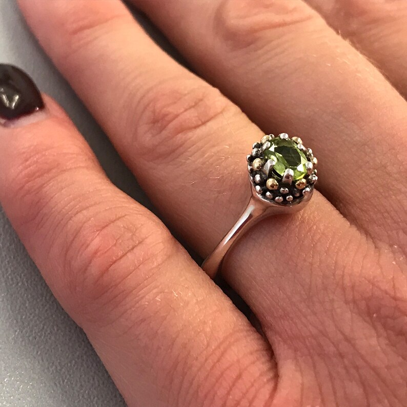 May include: A silver ring featuring a green gemstone set in a gold surround.