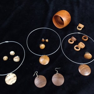 May include: A set of wooden jewelry featuring necklaces, earrings, and rings. The jewelry is made from different types of wood, each with its own unique grain pattern. The pieces are all natural and have a warm, earthy tone.