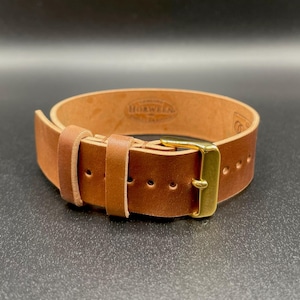 May include: A brown leather watch strap with a gold-colored buckle. The strap is made of thick, high-quality leather and features visible stitching and several adjustment holes. The brand name "HORWEEN" is stamped on the inside of the strap.