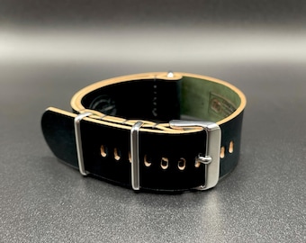 May include: A black leather watch strap with a silver buckle and keepers. The strap has a light brown underside and is designed to fit a watch. The strap is approximately 9 inches long.