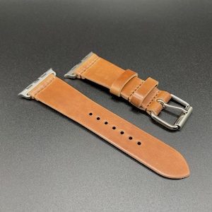 May include: Two brown leather watch bands with silver buckles. The bands are designed for Apple Watches.
