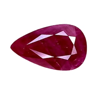 May include: A pear-shaped, faceted ruby gemstone. The gem is a deep, saturated red color with internal facets that reflect light. The shape is a teardrop, with a pointed end and a rounded top.