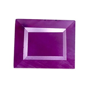 May include: A rectangular gemstone with a vibrant magenta purple hue and a faceted surface. The stone features a flat, smooth center panel surrounded by a beveled border that reflects light, creating a distinct frame effect on the top surface.
