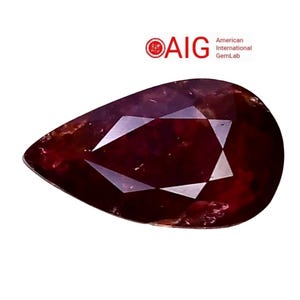 Peut inclure: Une pierre précieuse rouge foncé en forme de poire avec une surface à facettes, présentant des inclusions internes et des reflets lumineux. Le logo AIG American International GemLab est visible dans le coin supérieur droit sur fond blanc.