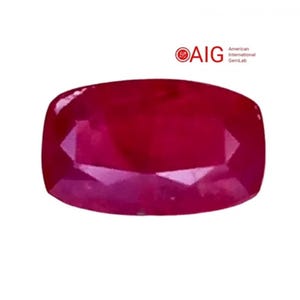 May include: A cushion-cut ruby gemstone with a deep red hue. The gem has a faceted surface that reflects light, creating a sparkling effect. The image includes the AIG logo and text.