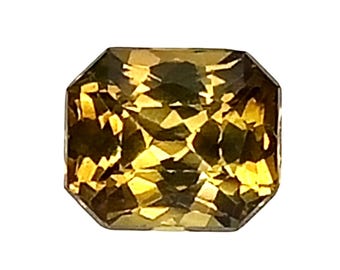 Peut inclure: Une pierre précieuse rectangulaire à facettes d'une teinte brun doré chaud. La pierre présente une taille précise avec de multiples facettes triangulaires et trapézoïdales qui reflètent la lumière, créant un motif contrasté ambre et jaune.