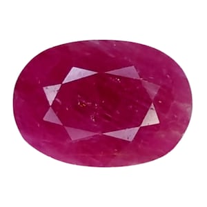 Puede incluir: Una gema de rubí facetada de forma ovalada. La gema es de un color rojo intenso y saturado con una superficie pulida. Las facetas crean un patrón de estrella en el centro de la piedra, reflejando la luz. El rubí está sobre un fondo blanco.