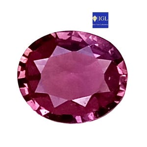 Op de afbeelding: Een ovaal geslepen, levendig roze edelsteen met een gefacetteerd oppervlak en een stervormig patroon in het midden. De steen vertoont diepe magentatinten en scherpe, geometrische randen door de hele structuur, met een klein IGL-logo in de hoek.