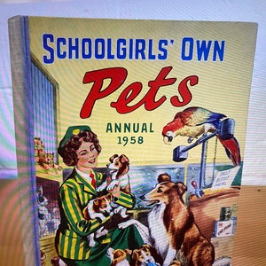 May include: A vintage book cover featuring a girl with a green and white striped shirt holding puppies. The book title is "Schoolgirls' Own Pets Annual 1958".