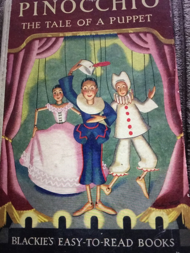 May include: Vintage children's book cover featuring a colorful illustration of Pinocchio, the puppet, and other characters on a stage. The title "PINOCCHIO THE TALE OF A PUPPET" is displayed above the illustration. The book is from "BLACKIE'S EASY-TO-READ BOOKS."