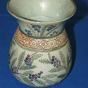 Può includere: Un vaso in ceramica bianca con un motivo floreale. Il vaso ha un'ampia apertura e un corpo arrotondato. Il motivo floreale presenta fiori blu, rossi e verdi.