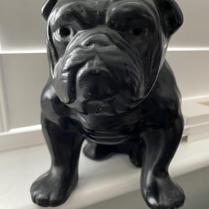May include: Black bulldog figurine, a solid, smooth, and detailed sculpture of a bulldog in a sitting position.