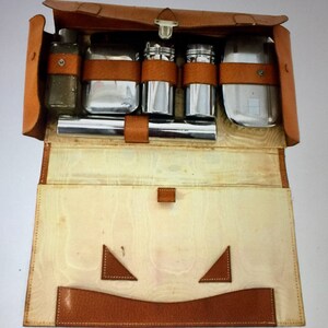Puede incluir: Un estuche de viaje de cuero marr&oacute;n con cierre de cremallera, que contiene un juego de herramientas de aseo plateadas, incluyendo una botella, una navaja, un peine y un cepillo.