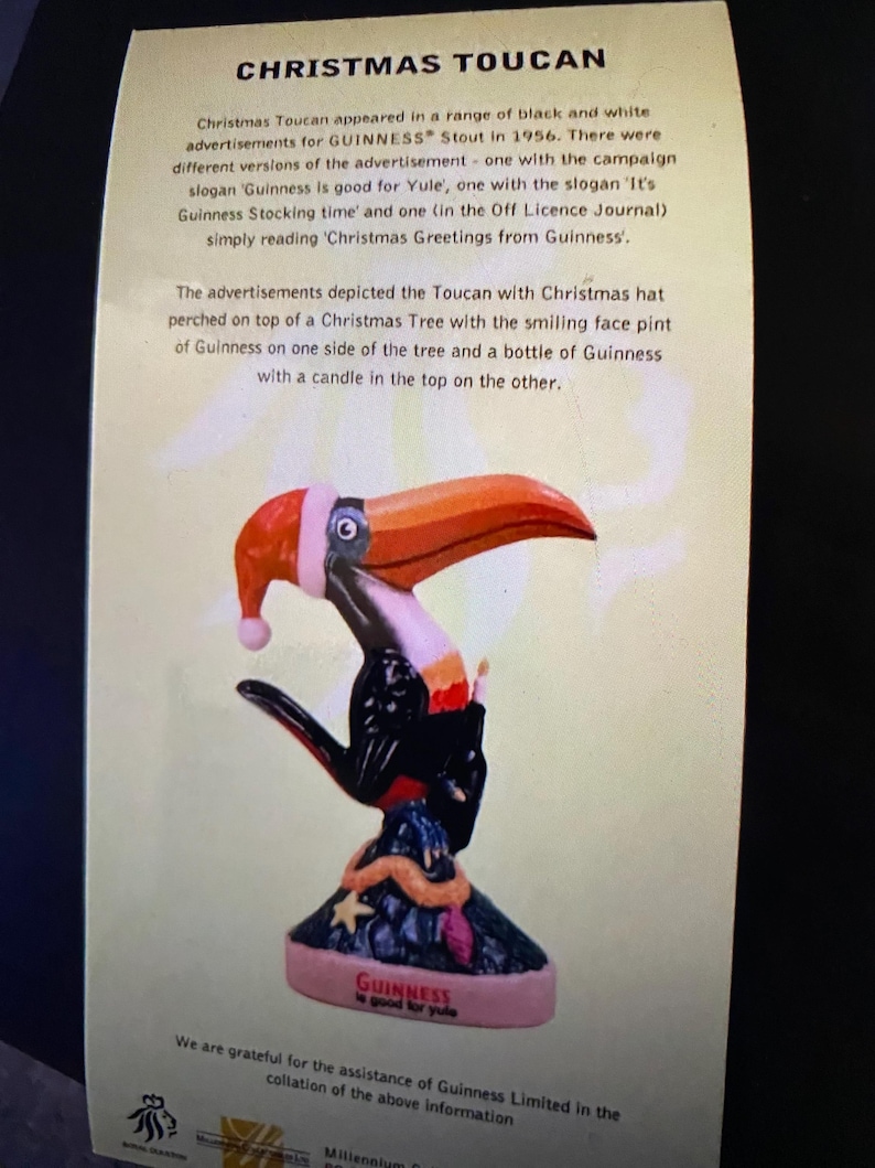 May include: A vintage Christmas advertisement for Guinness Stout featuring a toucan wearing a Santa hat perched on a Christmas tree. The toucan is holding a pint of Guinness and a bottle of Guinness with a candle on top. The text reads "Guinness is good for Yule".