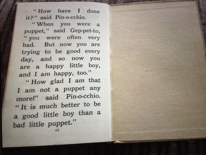May include: Open book pages with text from a children's story. The left page displays text from the story, including dialogue. The right page is blank. The text includes the words "Pin-o-cchio" and "puppet".