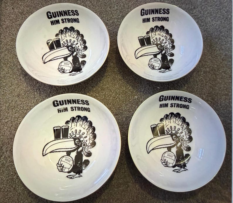 May include: Four white ceramic bowls with a black and white Guinness toucan design. Each bowl has the text "GUINNESS HIM STRONG" at the top. The toucan holds a rugby ball and two pints of Guinness.