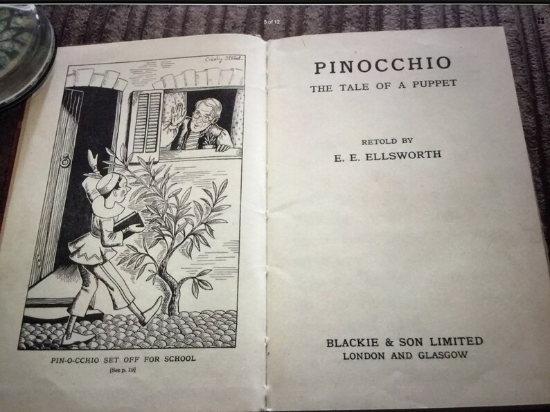 May include: An open book with the title "Pinocchio, The Tale of a Puppet" by E.E. Ellsworth. The left page features a black and white illustration of Pinocchio leaving for school. Published by Blackie & Son Limited, London and Glasgow.