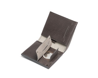 May include: A brown leather wallet with a coin pocket and multiple card slots. The wallet is open and the interior is visible.