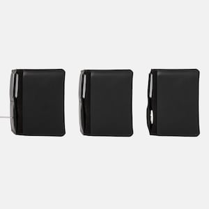 May include: Three black rectangular wallets arranged horizontally. Each wallet features a vertical side pocket containing a silver metallic tool or accessory. The wallets have a smooth, dark exterior finish and a compact, structured design.