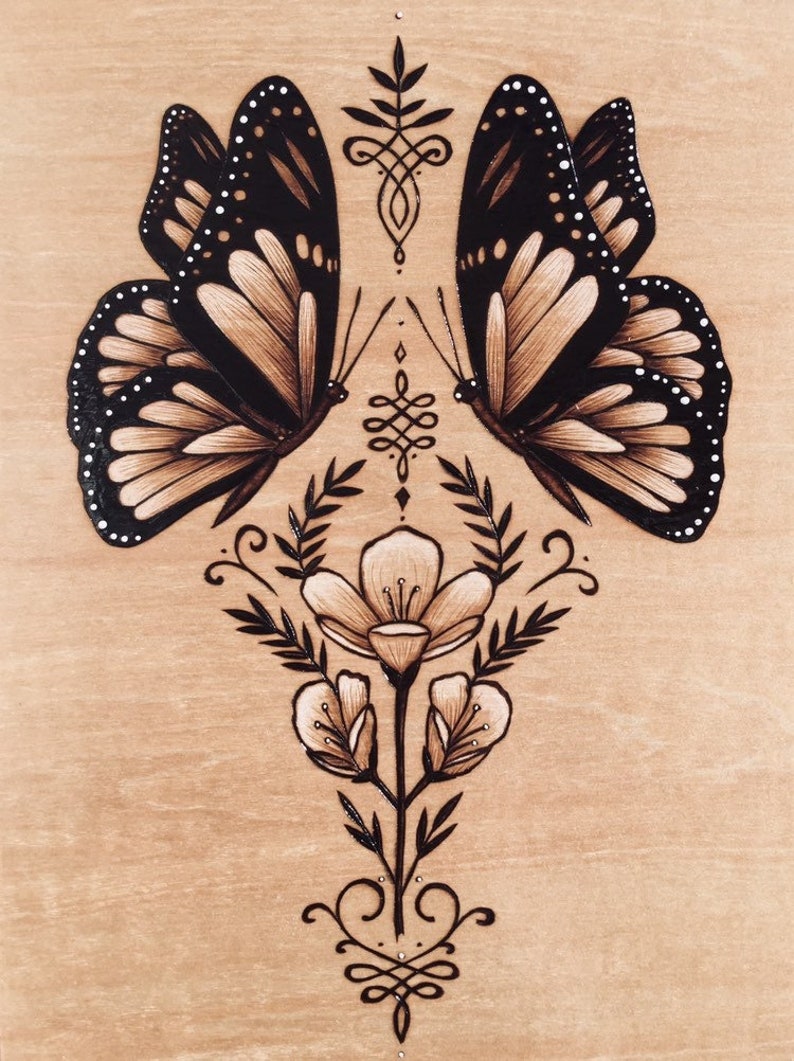 Art print that features a symmetrical arrangement. At the center of the design are two butterflies with layered wing, the butterflies face each other, creating a balanced and harmonious composition. Below are ornate flower buds blooming with leaves.