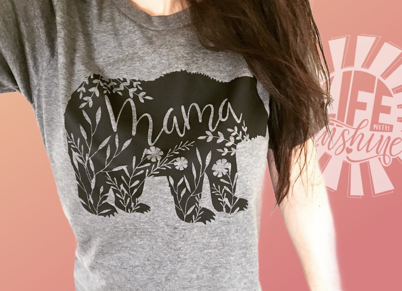 May include: Gray t-shirt with a black bear silhouette design. The bear is surrounded by floral details and the word "Mama" is written inside the bear.