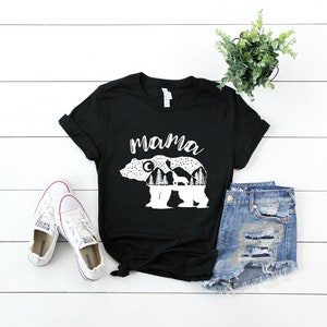 May include: Black t-shirt with a white graphic of a mama bear with cubs inside the outline of the bear. The text "mama" is above the bear.