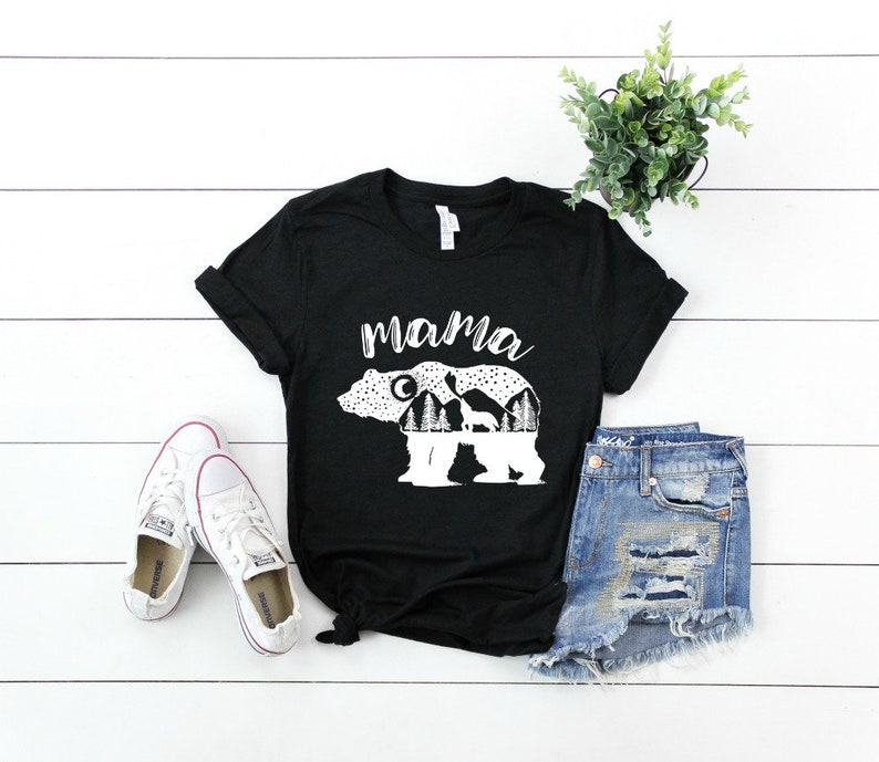 May include: Black t-shirt with a white graphic of a mama bear with cubs inside the outline of the bear. The text "mama" is above the bear.