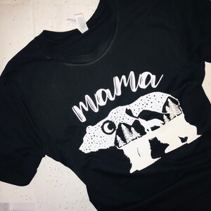 May include: Black t-shirt with a white graphic of a mama bear and two cubs with mountains and the word "mama" above them.