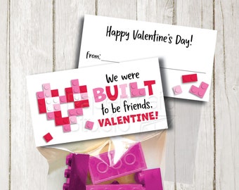 May include: Printable Valentine's Day card with a pink and red heart made of Lego bricks. The card says "We were BUILT to be friends. VALENTINE!" and has a space for a name. The card is next to a bag of pink and red Lego bricks.