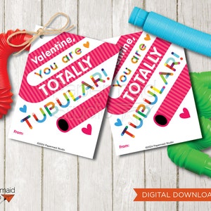 May include: Two Valentine's Day gift tags with the text "Valentine, You are TOTALLY TUBULAR!" in colorful letters. The tags are white with pink stripes and heart accents. Red, blue, and green pop tubes are scattered around the tags.