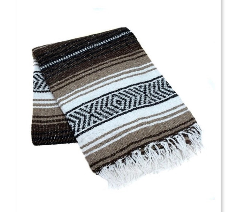 May include: A brown, white, and black striped Mexican blanket with fringe. The blanket is folded in half and has a woven pattern.