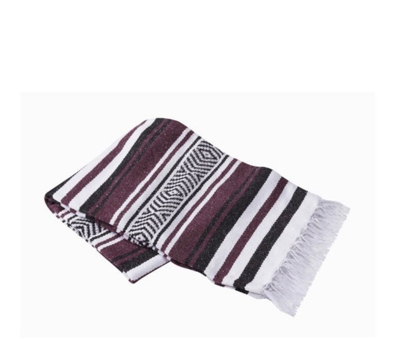 May include: A purple, black, and white striped Mexican blanket with fringe on the edges.