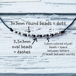 Puede incluir: Primer plano de un cord&oacute;n negro con cuentas plateadas. Las cuentas son redondas de 3 mm y ovaladas de 2,5 x 3 mm. El texto dice "3x3mm cuentas redondas = puntos", "2,5x3mm cuentas ovaladas = guiones", "1,6 mm cuentas miyuki de colores = espacio entre letras (2 cuentas entre palabras)".