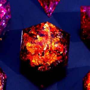 May include: A set of six iridescent dice with a variety of colors, including purple, red, and orange. The dice are made of resin and have a glittery finish.