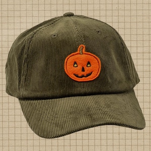 Peut inclure: Une casquette de baseball en velours côtelé vert olive avec un écusson brodé représentant une citrouille d'Halloween orange sur le devant. La casquette présente une calotte structurée, une visière incurvée et des œillets cousus.
