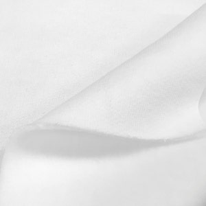 May include: Close-up of a white fabric with a soft, textured surface. The fabric is folded over itself, creating a smooth, curved line.