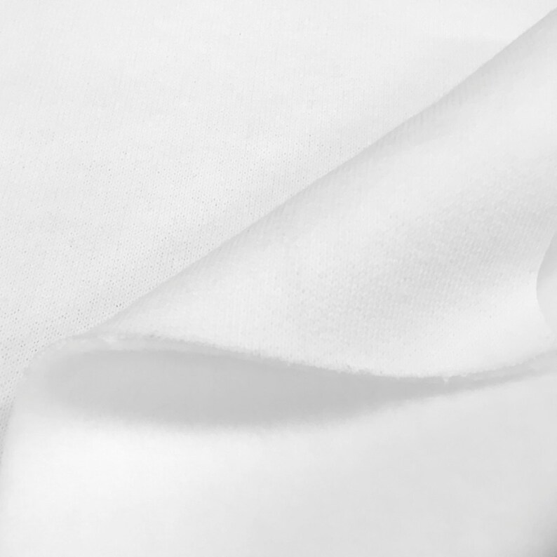 May include: Close-up of a white fabric with a soft, textured surface. The fabric is folded over itself, creating a smooth, curved line.